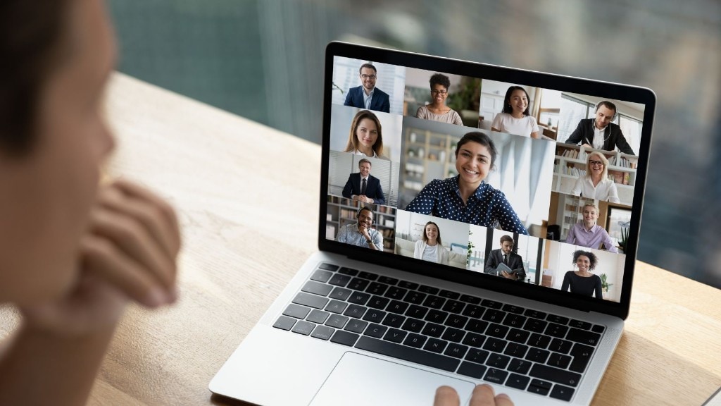 Person attending a large video call with nine participants visible on a laptop screen